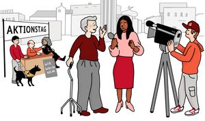 Unter einem Banner sitzen und stehen drei Personen und ein Assistenzhund. Auf dem Banner steht: Aktionstag. Vorn im Bild ist ein Mann mit grauem Haar und Gehhilfe. Er spricht mit einer Reporterin. Die beiden werden von einem Kameramann gefilmt.